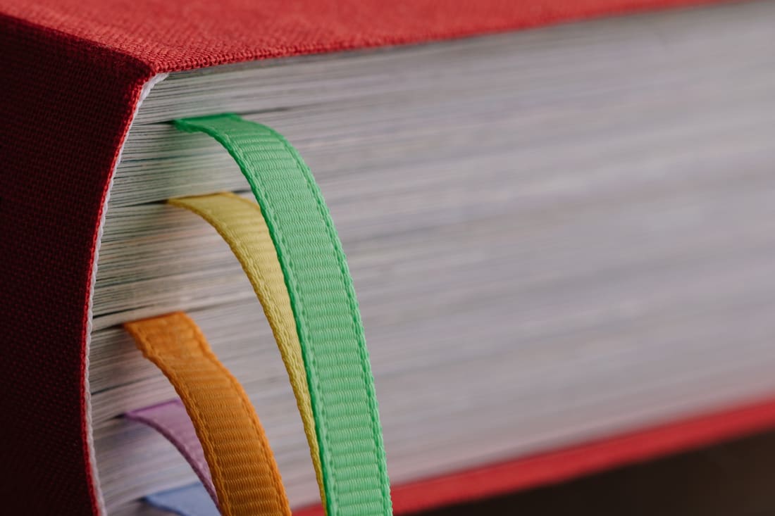 Close-up of a cloth-bound book with several colored ribbon markers